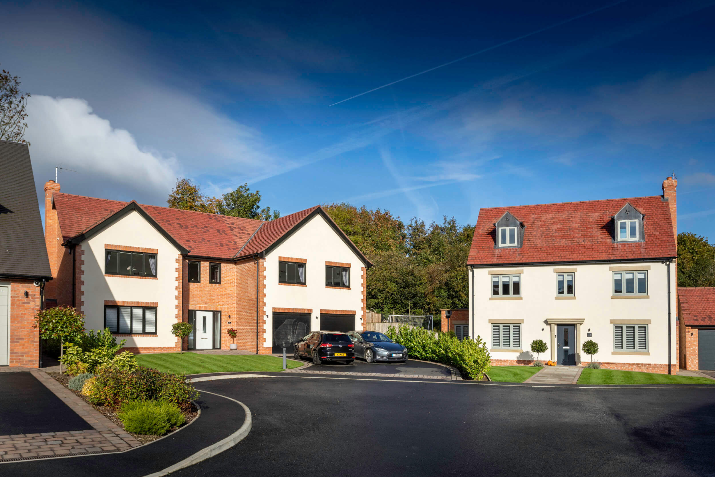New build development properties featuring a mix of black and sage green Profile22 uPVC windows and doors on a tarmac driveway.