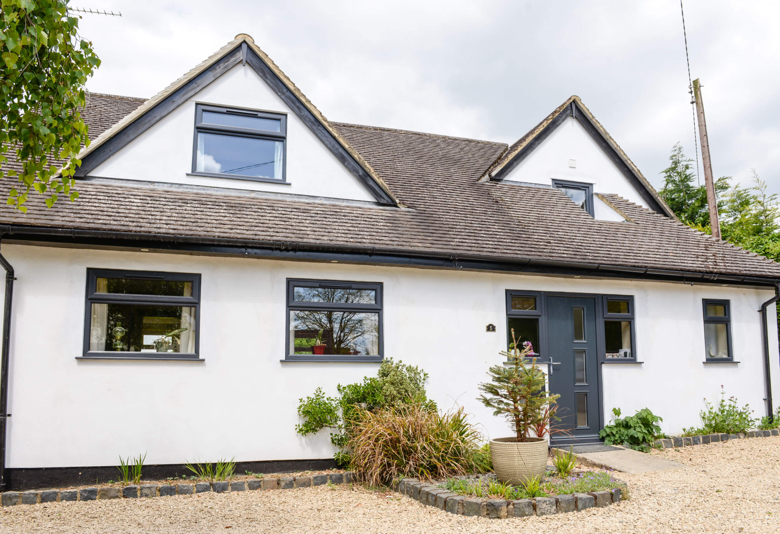 White rendered cottage renovated with anthracite grey Profile22 Optima sculptured window frames and a matching modern uPVC entrance door.